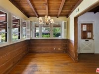 Room with wood walls, wood floor, beam ceiling, windows, and light fixture