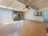 Living room with wood floor, ceiling fan, big windows, and glass door to patio