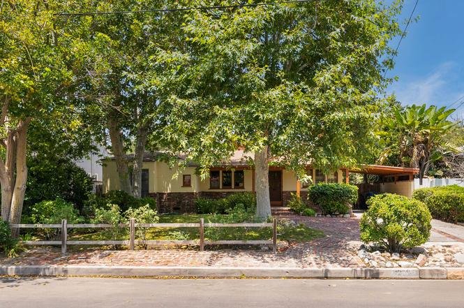 California real estate yellow house with trees, yard, and driveway