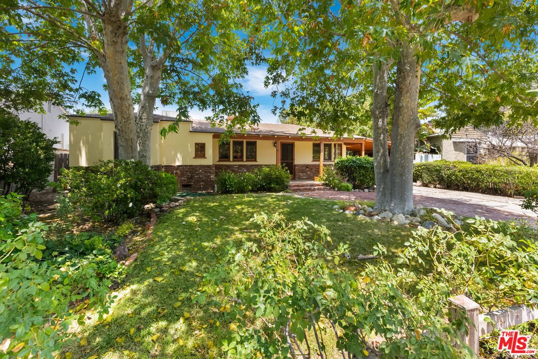 California real estate house with porch, stone accents, trees, and green shrubs