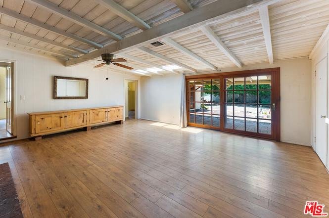 Room with wood floor, fan, big windows, sideboard, and beam ceiling