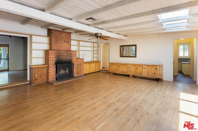 Living room with wood floor, brick fireplace, cabinets, fan, and big windows