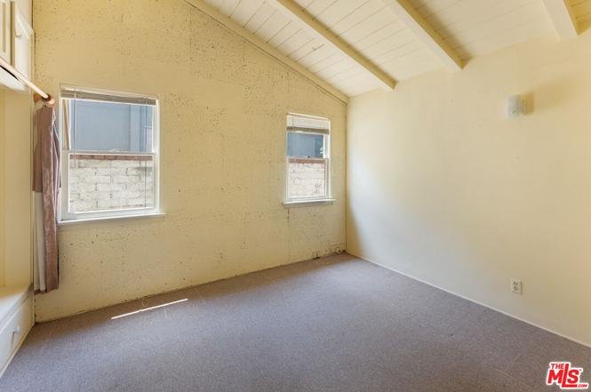 Room with two windows, high ceiling with wood beams, and carpet floor