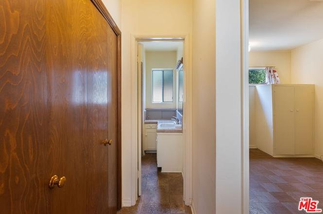 Hallway leading to bathroom and laundry area with door on the left
