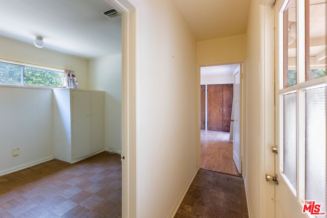 Hallway with window, doors to rooms, tile floor, and wood floor