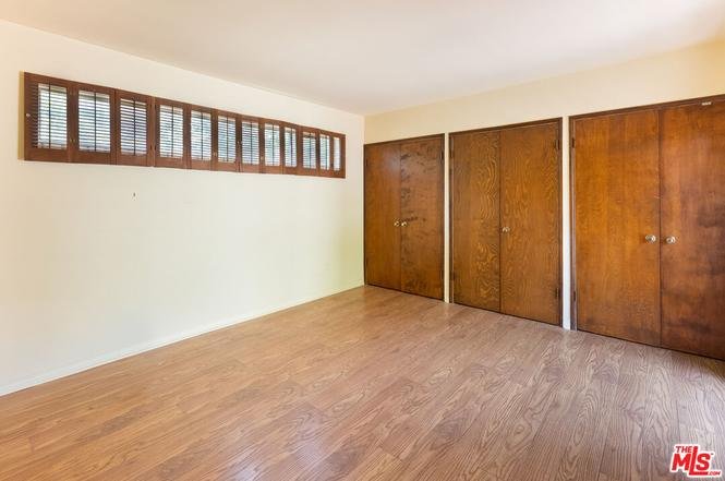 Room with wood floor, wooden doors, and windows