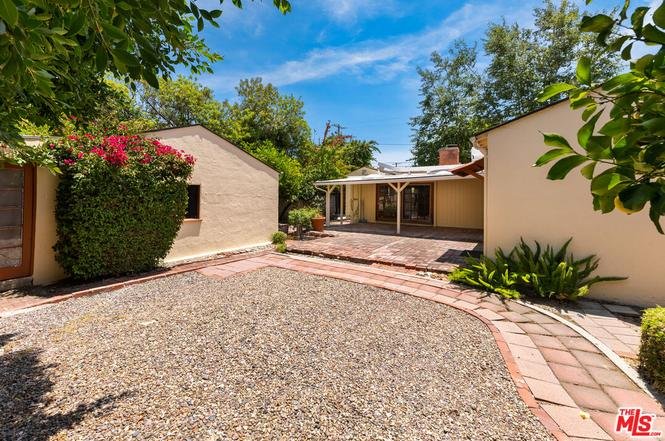 California real estate gravel yard with flowers and patio next to house