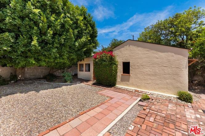 California real estate house with gravel yard, brick path, trees, and green plants