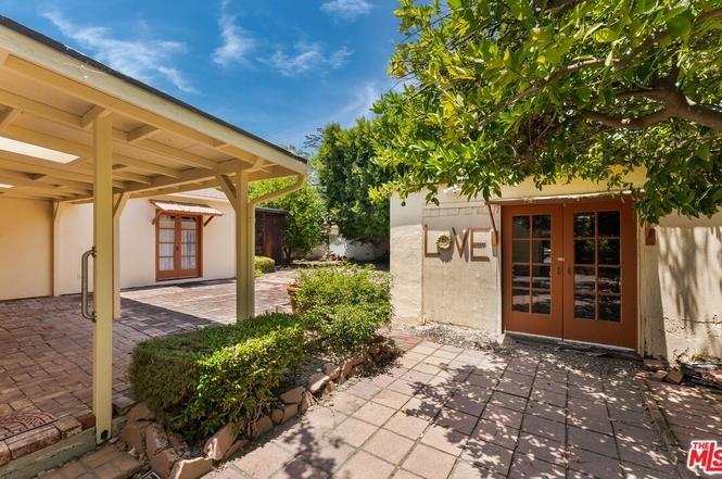 Patio with stone floor, green bushes, trees, and building with word LOVE