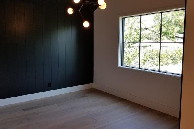 Room with black walls, wooden floor, and large window.