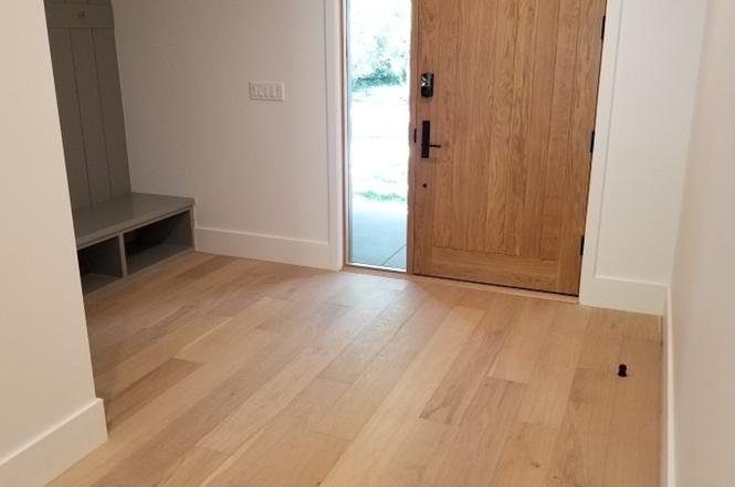 Hallway with wooden floor, door, and small bench.