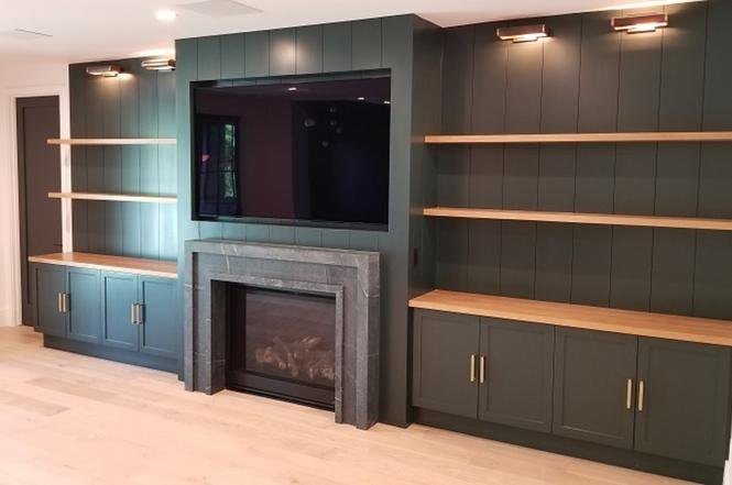 Living room with dark green wall, built-in shelves, and fireplace.