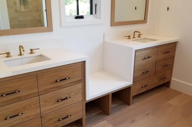 Bathroom with two sinks, gold faucets, and wooden cabinets.