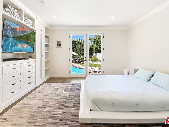 Bedroom with bed, wall TV, shelves, and glass doors to pool area.