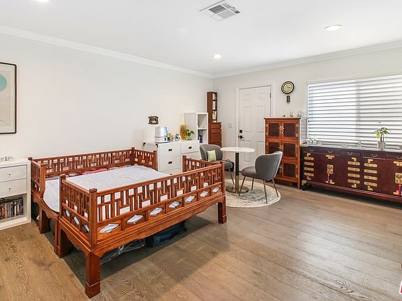 Room with crib, table, chairs, cabinet, and large windows.