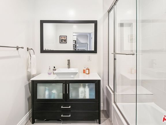 Bathroom with black vanity, sink, mirror, towel rack, and glass shower.