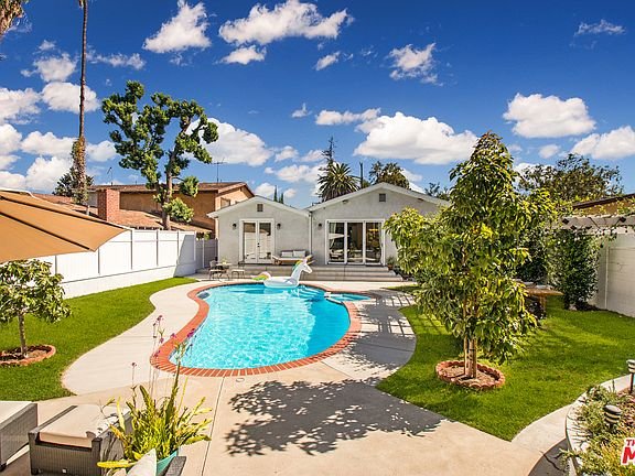 Backyard pool with grass and plants in California real estate.