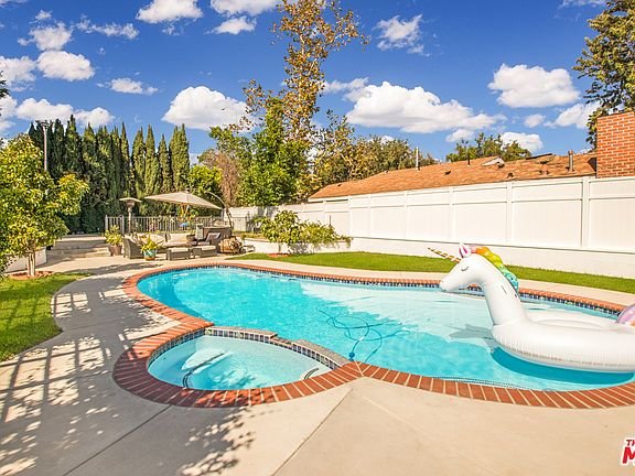 Backyard pool with unicorn float and trees in California real estate.