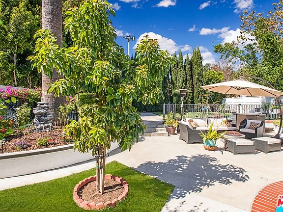 Backyard dining table with plates, patio cover, pool, and plants.
