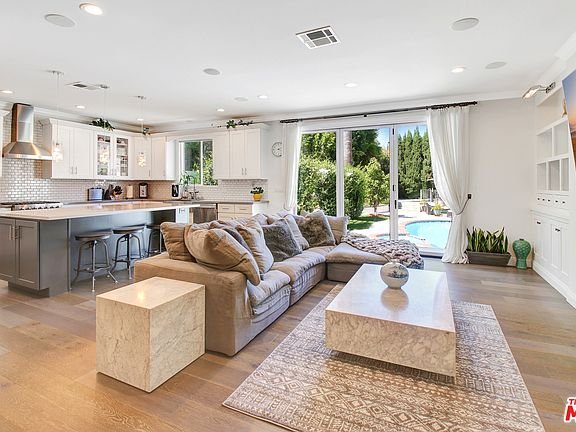 Living room with large sofa, coffee table, and glass doors to pool backyard.