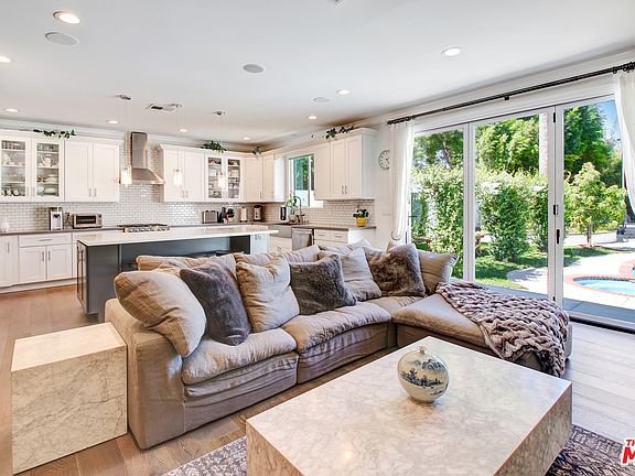 Living room with gray sofa, pillows, coffee table, and glass doors to backyard.