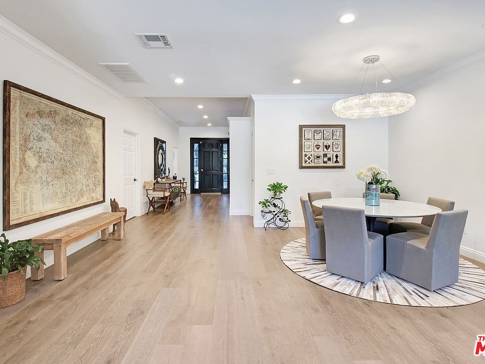 Dining area with round table, gray chairs, rug, plants, bench