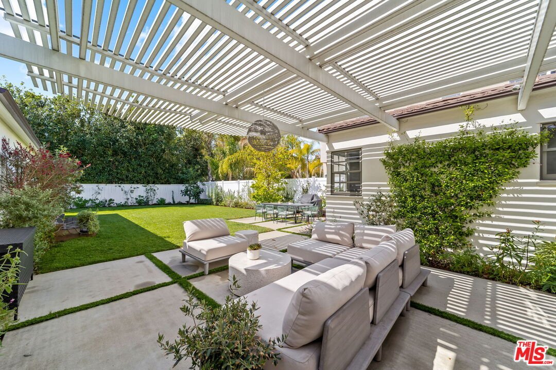California real estate house patio with seating, pergola, green lawn, and garden.