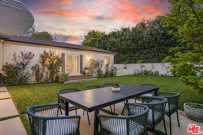 California real estate house outdoor dining area with table, chairs, garden, and trees.