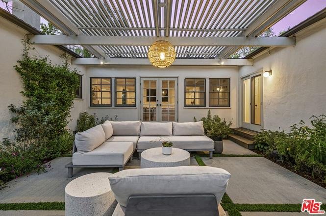 California real estate house patio with sectional sofa, round coffee table, and garden.