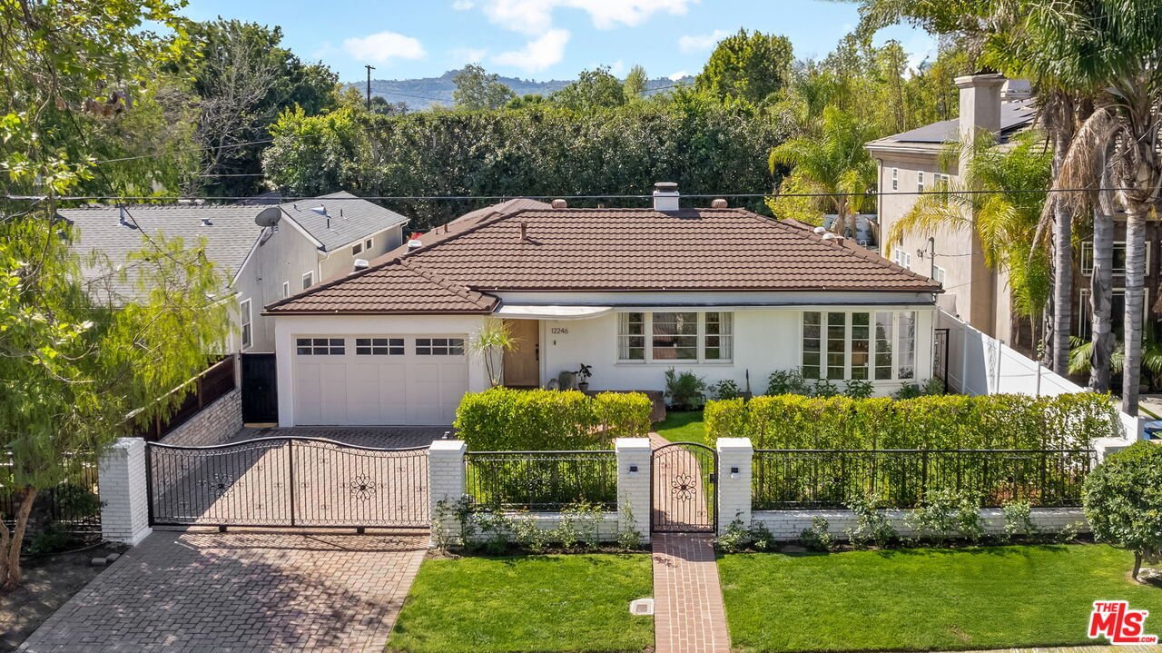 California real estate house with brown tile roof, white walls, green lawn, driveway, and garage.