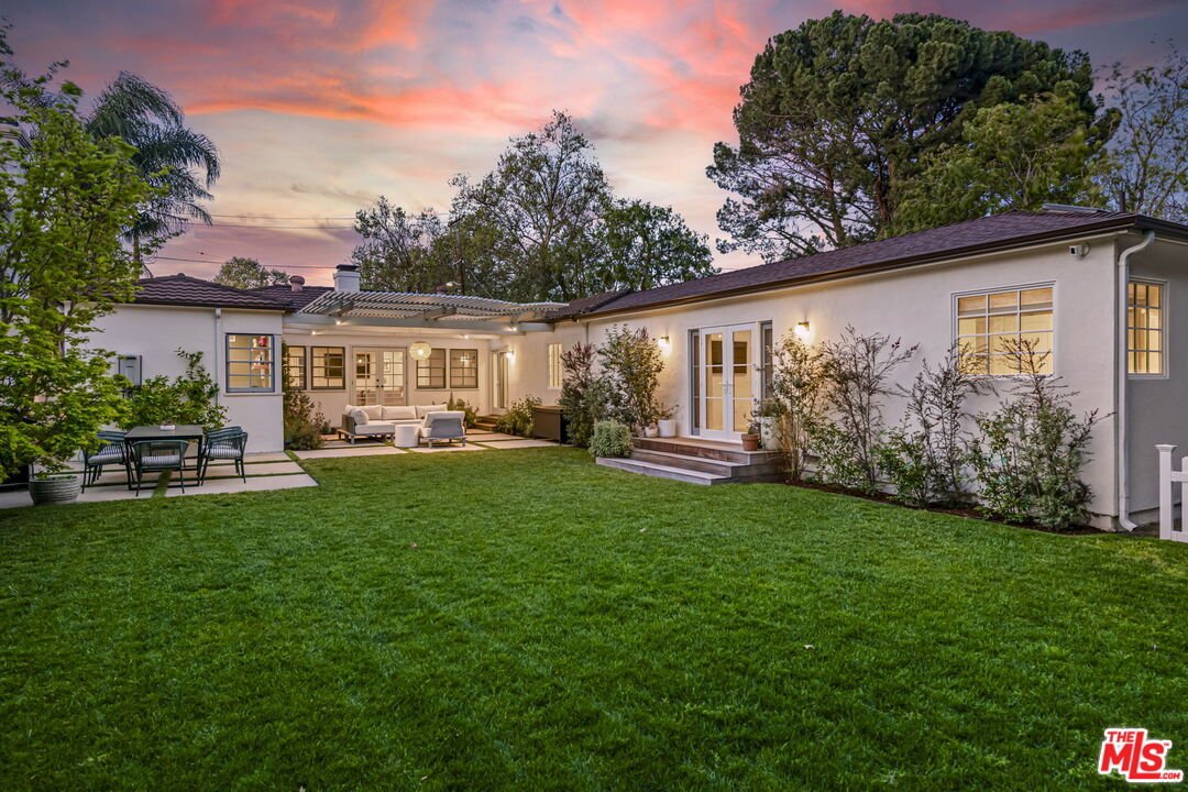 Luxury California real estate house backyard with lawn, patio seating, and garden.