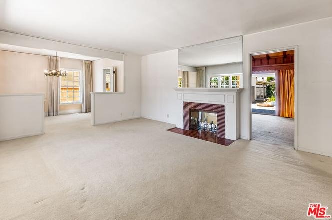 Living room with carpet, brick fireplace, large windows, and open walkway.