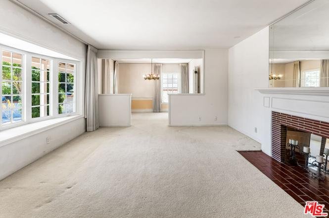 Living room with beige carpet, fireplace, and large windows.