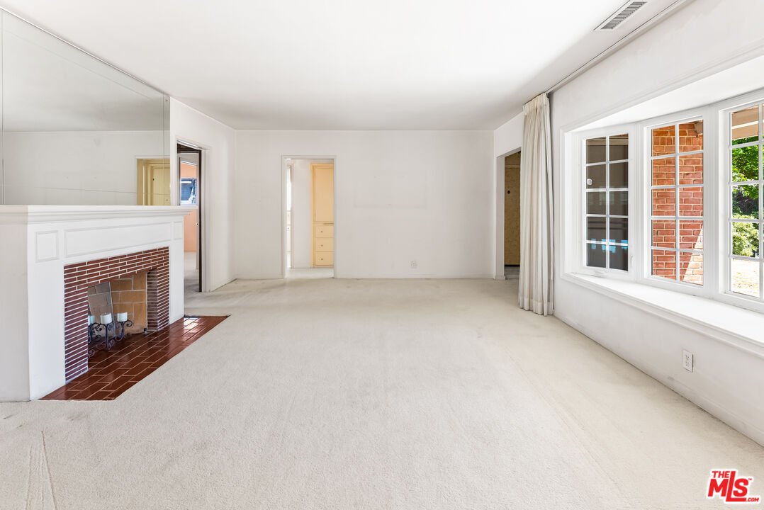 Living room with fireplace, large windows, and light floors.