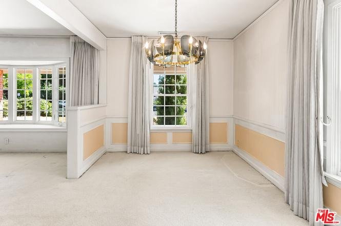 Empty room with white walls, carpet, and large windows.