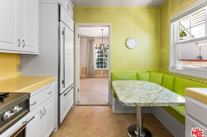 Kitchen with yellow and green decor, marble table, and curved bench.