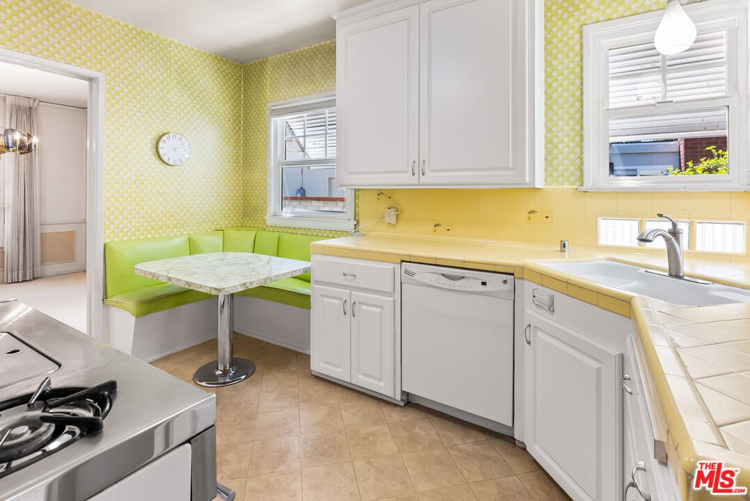 Kitchen with green wallpaper, white table, and green seats.