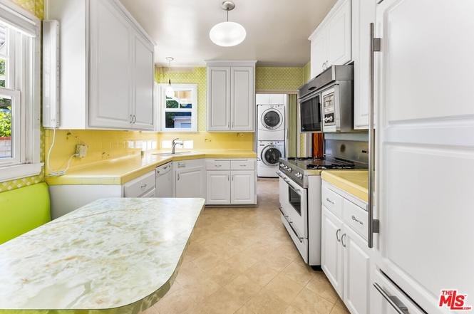 Kitchen with yellow walls, white cabinets, and marble table.