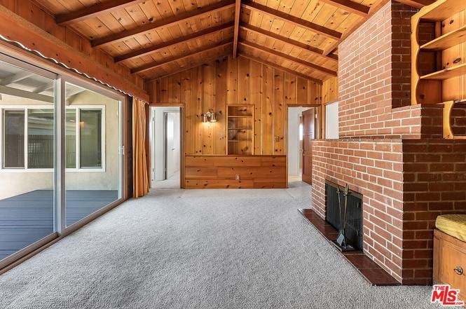 Living room with wooden beams, brick fireplace, and sliding glass doors.