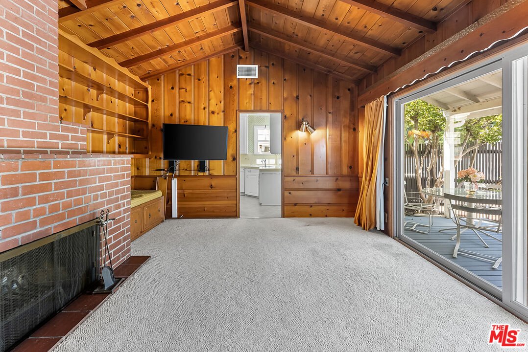 Living room with wooden walls, brick fireplace, and sliding glass doors.