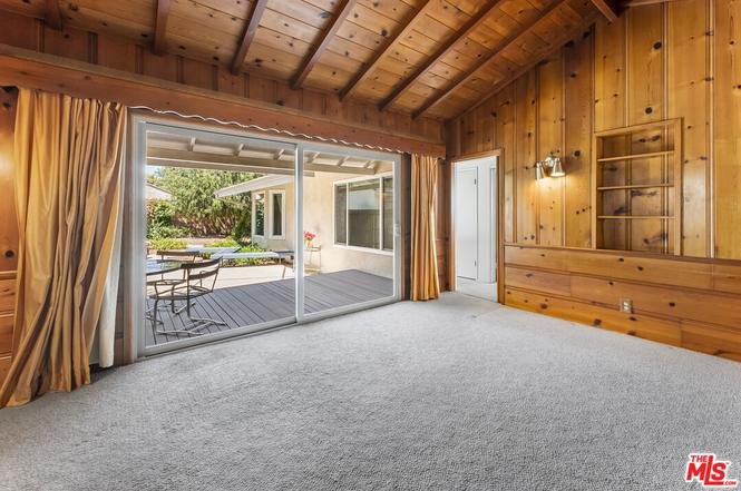 Room with wooden walls, sliding glass doors, and carpet.