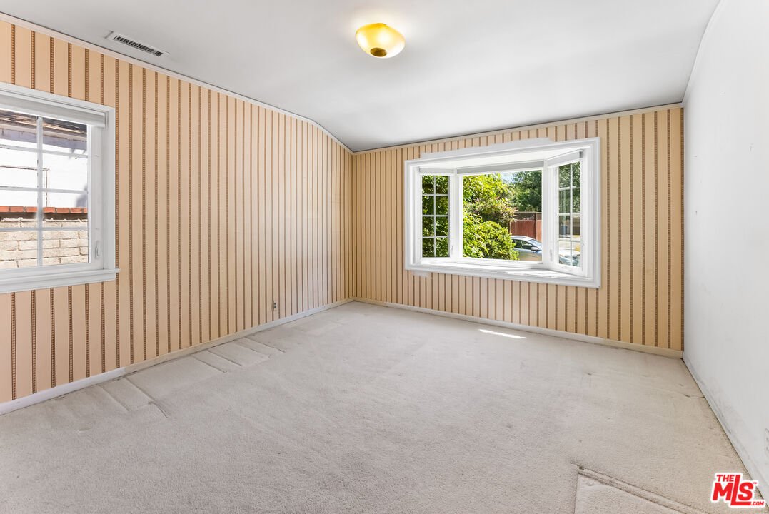 Empty room with beige walls, carpet, and large window.