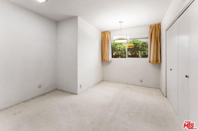 Empty room with white walls and window with yellow curtains.