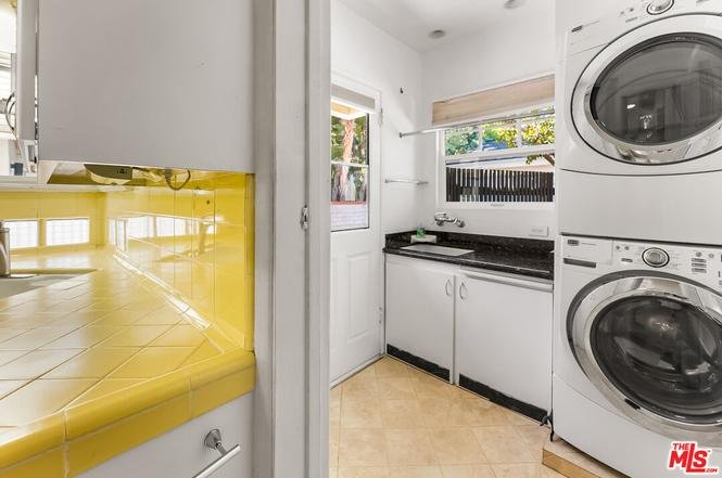 Laundry room with stacked washer and dryer and yellow tiles.