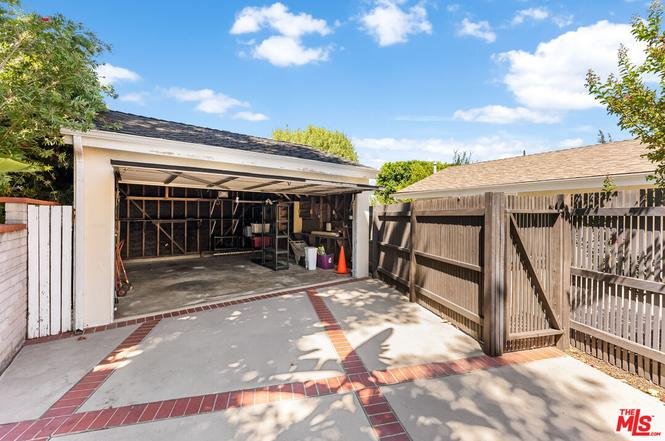 Garage with open door, cement driveway, and wooden fence.