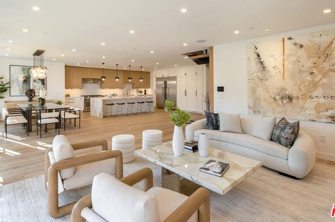 Living room with soft seats, coffee table, big glass doors to patio, and dining area.