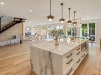 Kitchen with large marble island, pendant lights, wooden floors, and large windows