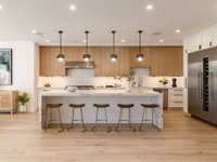 Kitchen with wooden cabinets, large island with seating, pendant lights, and stainless steel appliances