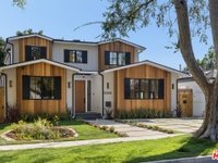 California real estate home with two stories, wooden and white siding, large windows, and landscaped front yard