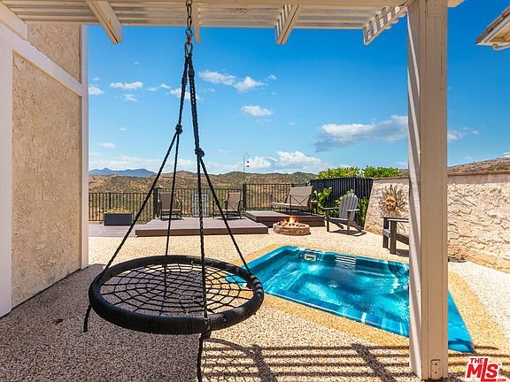 Patio with hanging chair, pool, and mountain view California real estate.